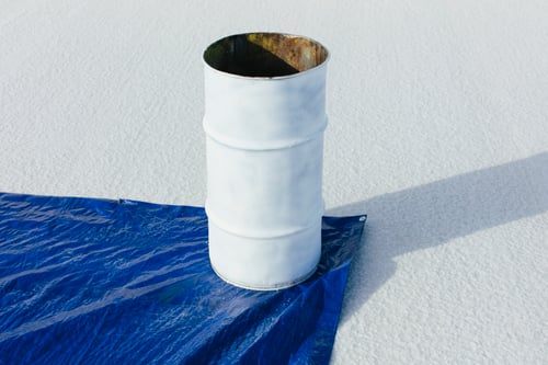 Blue waterproofing membrane laid over a white commercial roof surface