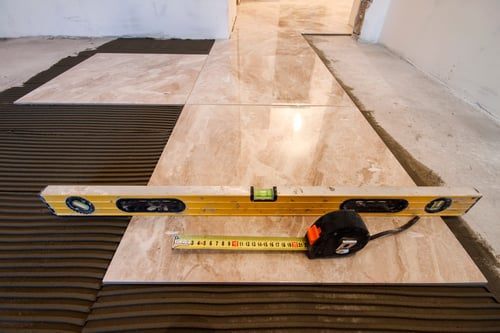 Large-format tile being set over a waterproofing membrane on a prepared floor